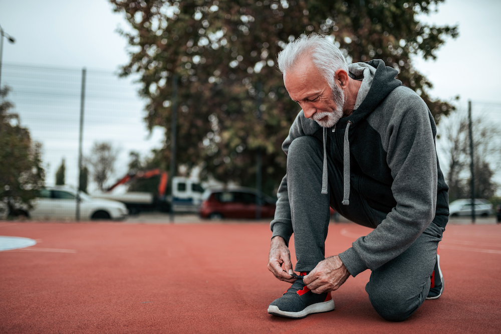 A senior man tying his shoe before a walk around his independent living facility