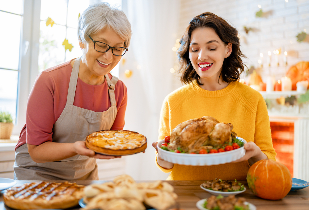 Senior woman and her daughter holding up dishes on Thanksgiving day